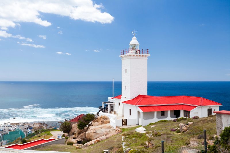 Der weiße Leuchtturm von Cape St Blaize mit rotem Dach, dahinter das Meer